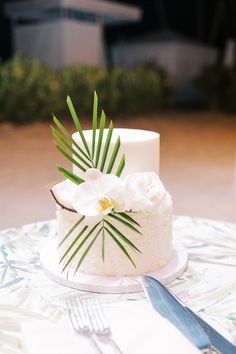 a wedding cake with white flowers and palm leaves