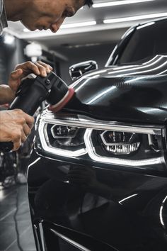 a man is working on a car's headlight in a garage with other cars