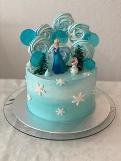 a frozen princess themed cake with frosting and decorations on the top, sitting on a glass platter