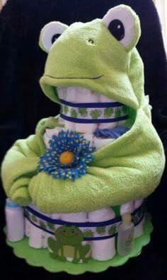 a green frog diaper cake sitting on top of a table