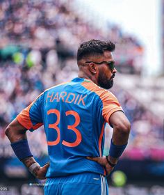 a man with his hands on his hips standing in front of a stadium full of people