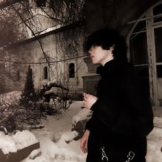 a woman standing in front of a house covered in snow with her hand on her hip