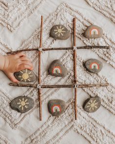 a child playing with rocks and sticks on a bed covered in white linens,