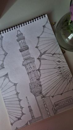 a drawing of a mosque on top of a table next to a vase with flowers