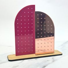 a pink and black sculpture with holes in it's sides on a wooden stand