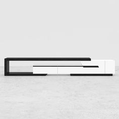 a modern white and black tv stand on concrete floor with minimalist style furniture in the background