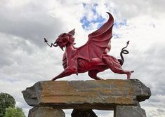 a statue of a red dragon sitting on top of a rock