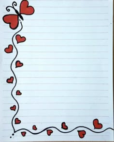 a sheet of lined paper with red hearts and a butterfly on the corner, in front of