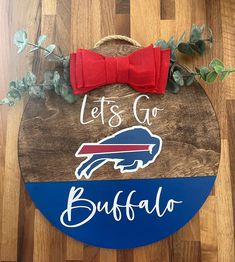 a wooden sign that says let's go buffalo with a red bow on it