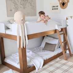 a little boy sitting on top of a bunk bed with an octopus stuffed animal next to him