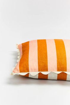 an orange and white striped pillow with scalloped edges