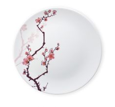 a white plate with pink flowers and branches on the rim, against a white background