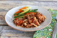 a white plate topped with meat and veggies on top of a wooden table