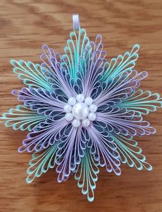 an ornament made out of paper on top of a wooden table with beads