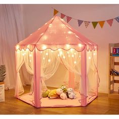 a pink tent with lights and stuffed animals