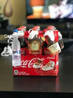 coca - cola bottles are sitting in a red box on a table next to a christmas ornament