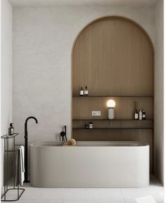 a bath tub sitting next to a shelf filled with bottles and candles on top of it