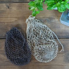 two bags sitting on top of a wooden table next to a plant in a pot