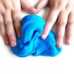 two hands touching something blue on a white surface