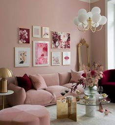 a living room with pink furniture and pictures on the wall