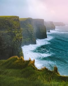 the cliffs are covered in green grass near the ocean