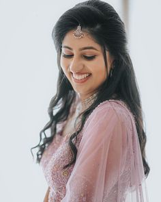 a woman in a pink dress smiles at the camera