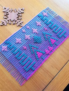 a wooden table topped with a blue and pink rug next to a pair of scissors