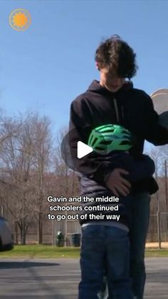 a man holding a skateboard while standing next to a person on a skateboard