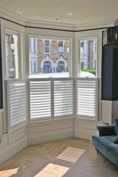 a living room filled with furniture and windows covered in shuttered glass doors, along with hardwood flooring