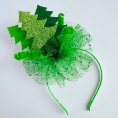 a green and white flower with leaves on it's headband, sitting next to each other