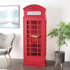 a red phone booth next to a chair and potted plant in a living room