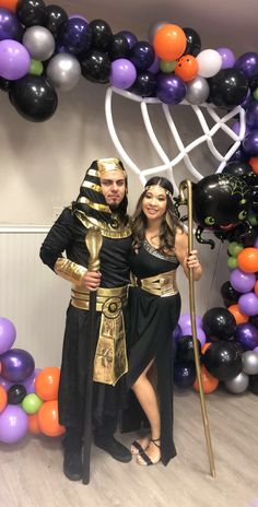 a man and woman dressed up in egyptian garb posing for a photo with balloons behind them