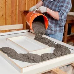 a man pouring cement into an unfinished cabinet