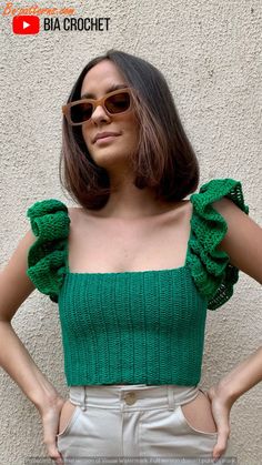 a woman wearing sunglasses standing in front of a wall with her hands on her hips