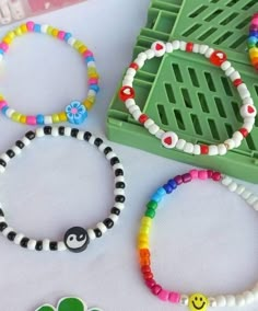 four bracelets with smiley faces on them are sitting next to a green tray and plastic brochure