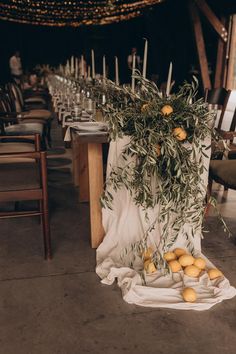 an arrangement of lemons and greenery on a table at a wedding reception with candles in the background