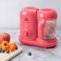 an orange juicer next to a cutting board with blueberries and apples on it