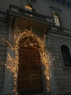 a large building with lights on it's doors and trees in front of the door