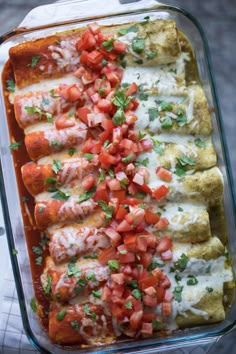 an enchilada dish is topped with tomatoes and cilantro