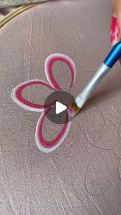 someone is using a needle to stitch a flower on a piece of fabric with pink and blue thread