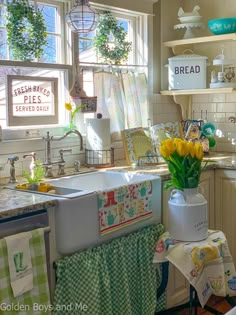 a kitchen with yellow tulips in a white vase on the sink and green checkered curtains