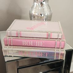 three books stacked on top of each other in front of a disco ball and mirror