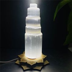 a tall white cake sitting on top of a table next to a light that is turned on