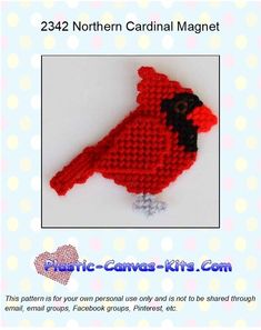 a crocheted red bird sitting on top of a white table next to polka dots