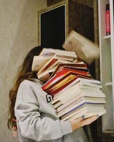 a girl holding a stack of books in front of her face