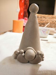 a clay gnome's hat sitting on top of a white tablecloth covered table