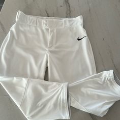 a pair of white shorts with black nike logo on the front and bottom, sitting on a marble surface