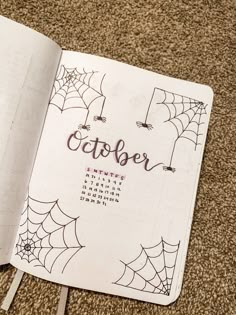 an open notebook with the word october written on it and spider webs in the background