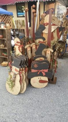 several wooden snowmen with hats and skis on display in front of a store