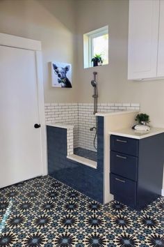 a bathroom with blue and white tiles on the floor, sink and shower stall in it